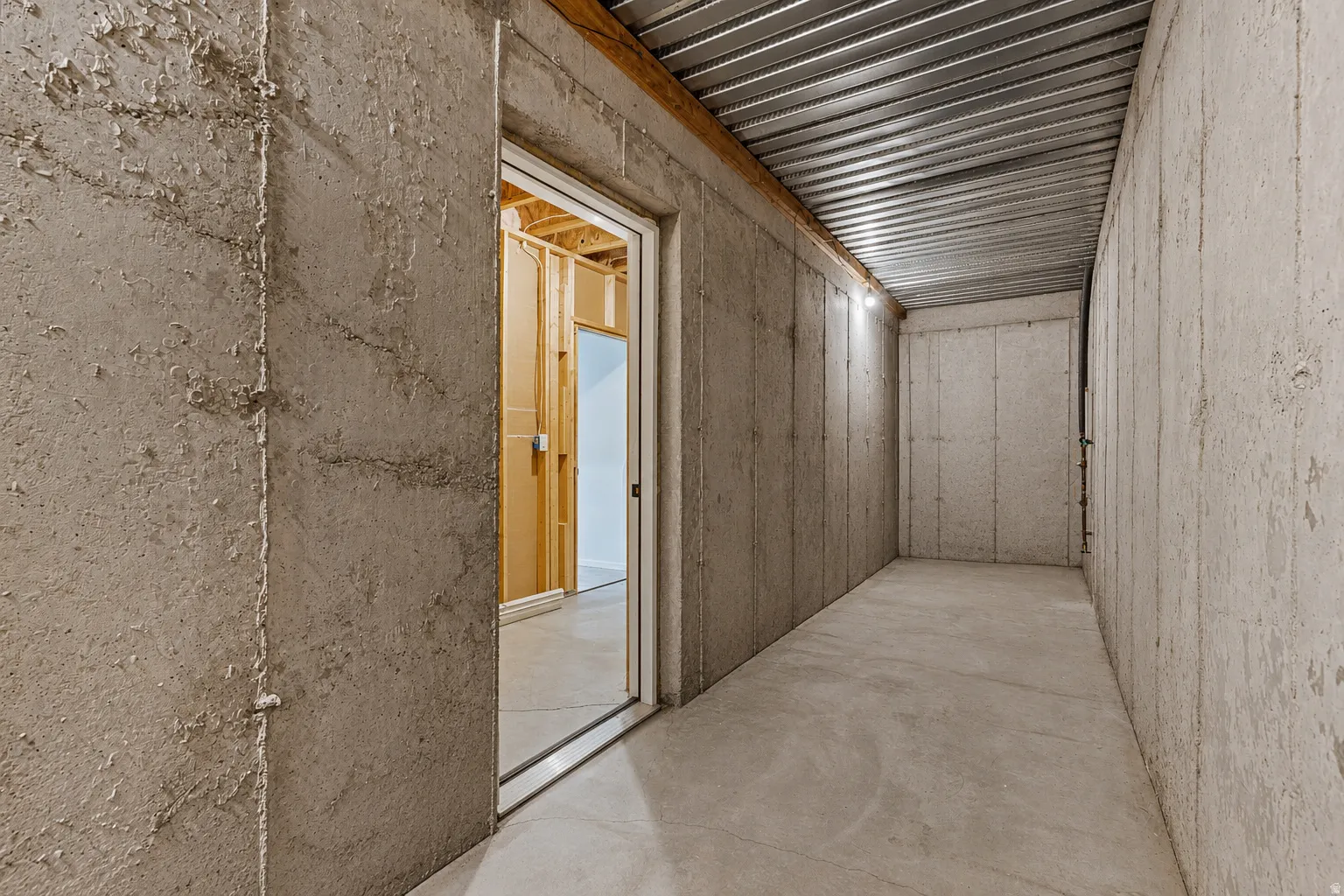 Unfinished basement space featuring concrete walls, a concrete floor, and a metal ceiling