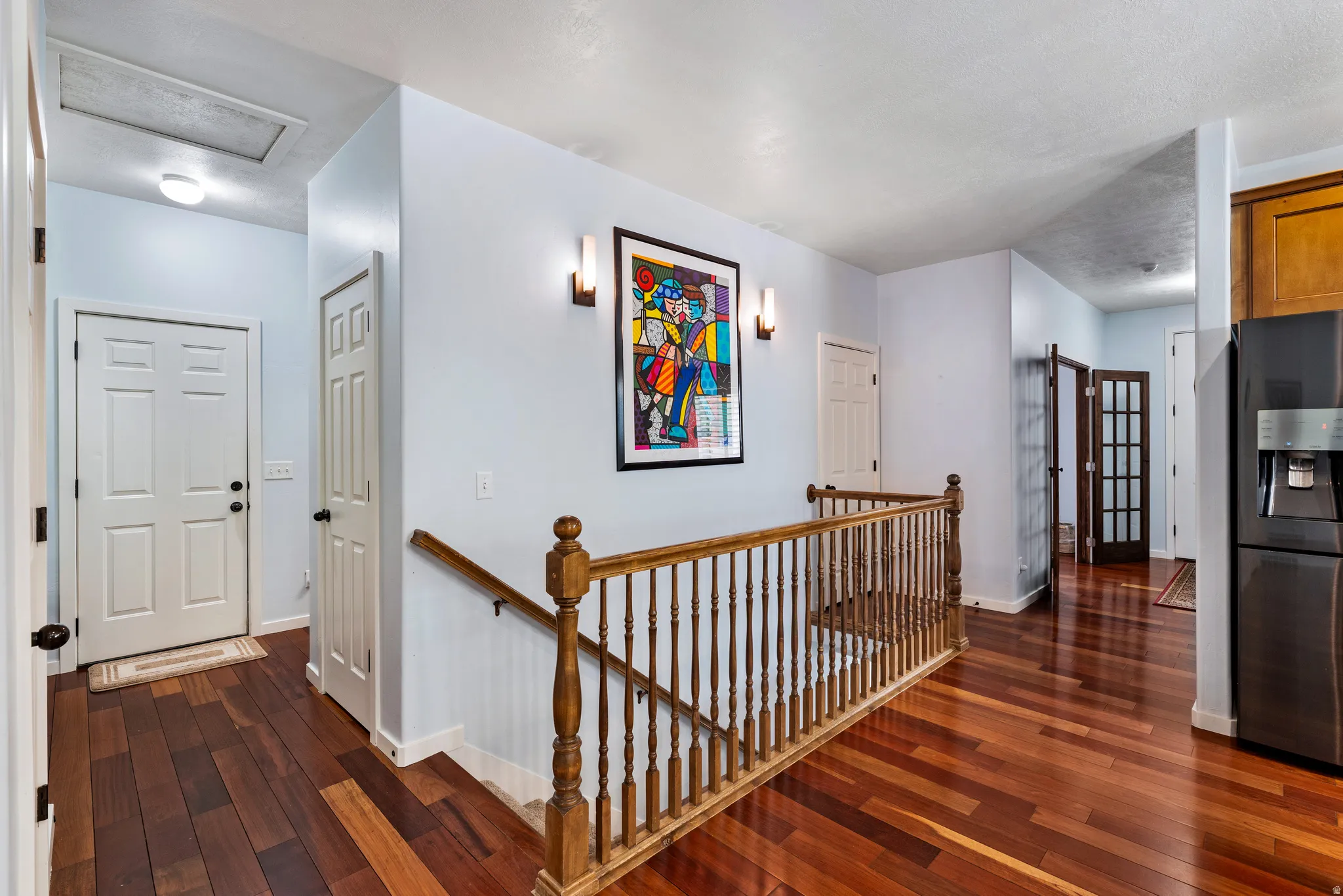 Hardwood flooring spanning the hallway and staircase, featuring a traditional wood banister