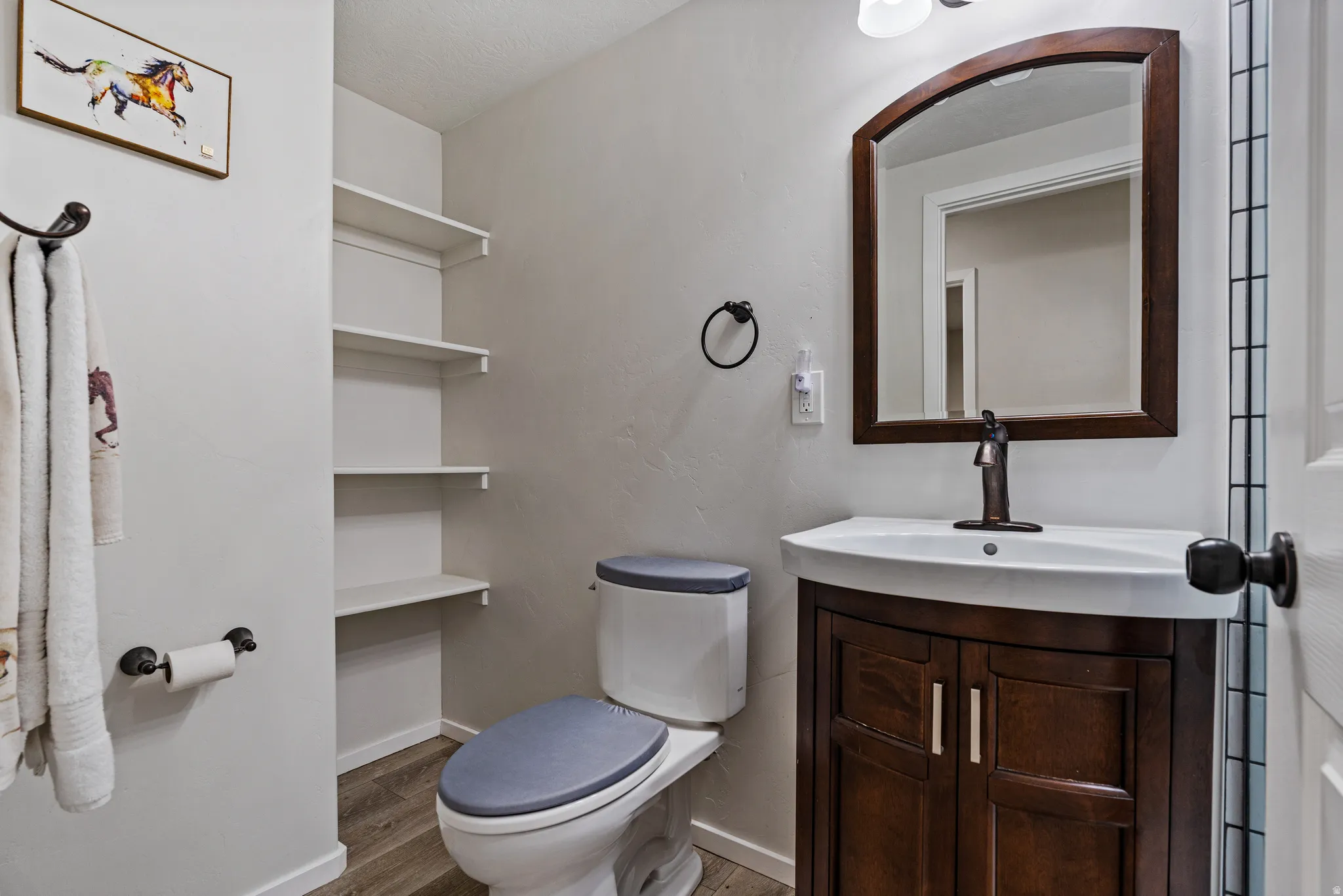 Bathroom featuring a dark wood-finish vanity with a white integrated sink and bronze-finish faucet