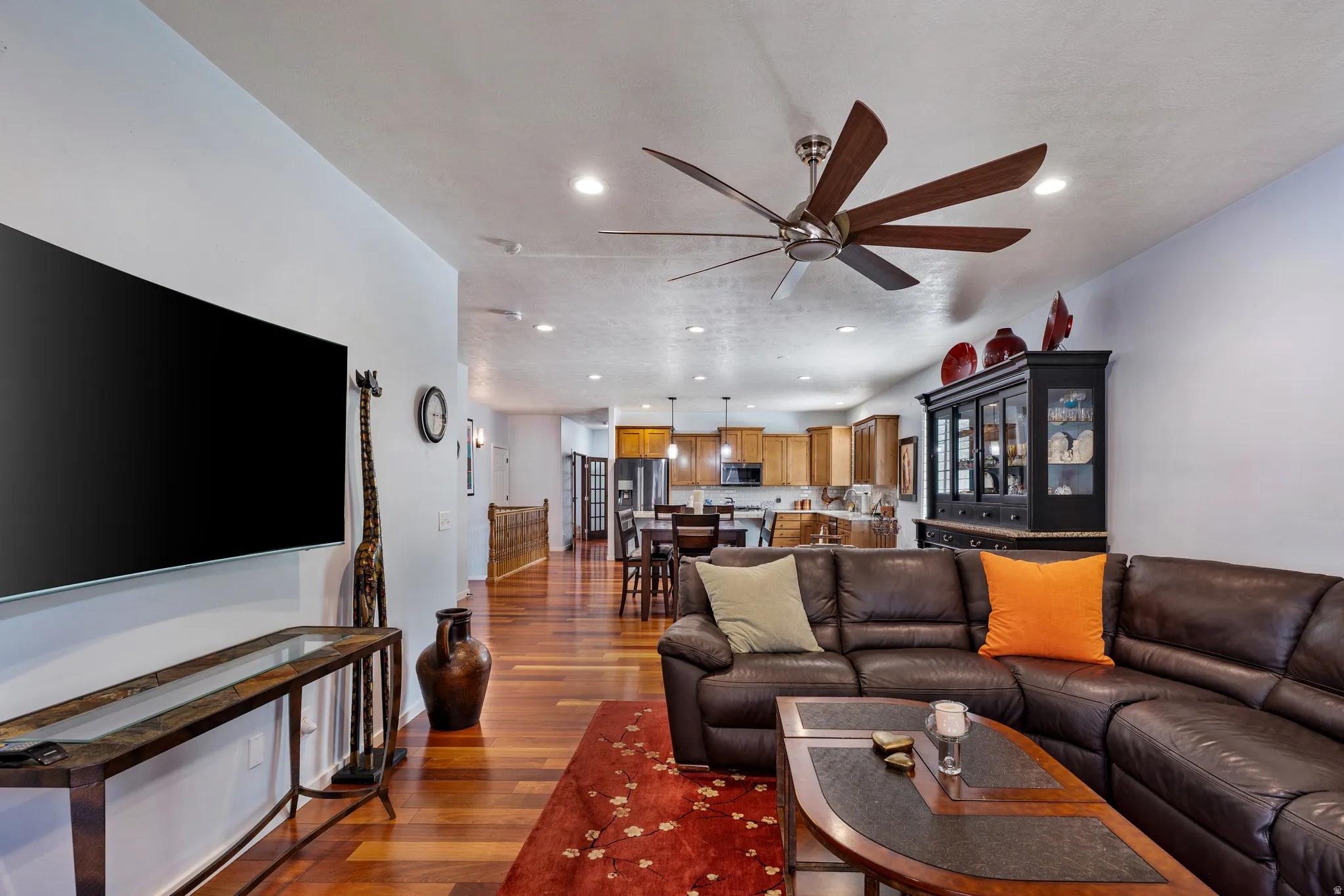 Open-concept living space featuring wood-finish flooring, recessed lighting, and a multi-blade ceiling fan