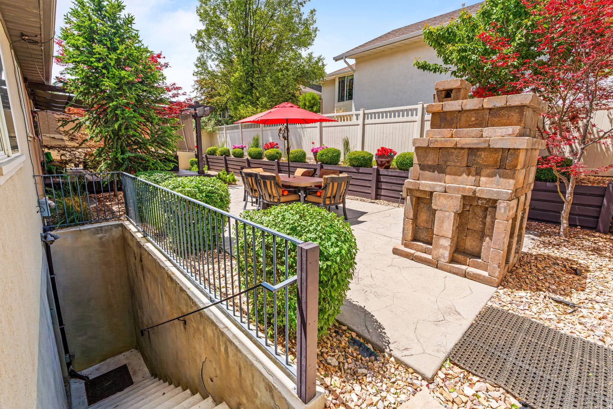 Expansive patio area featuring stamped concrete, a decorative stone structure, and perimeter landscaping