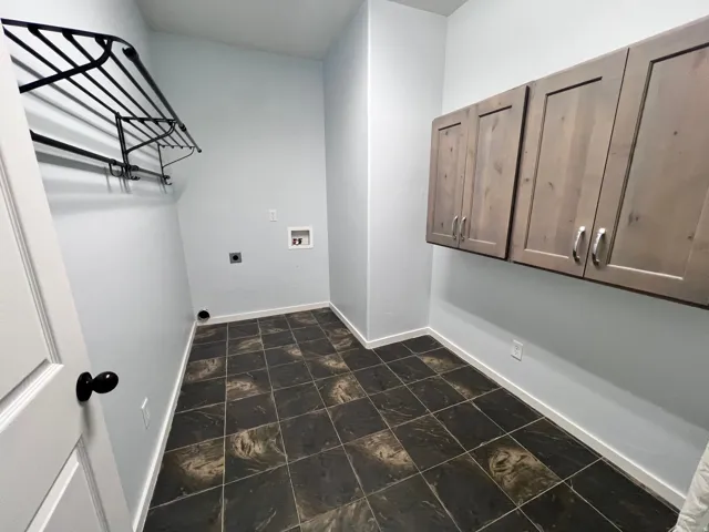 Utility room featuring dark patterned floor tiling and light blue walls