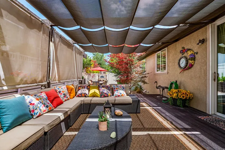 Covered patio area featuring a retractable fabric shade system, wood-finish decking, and an outdoor area rug