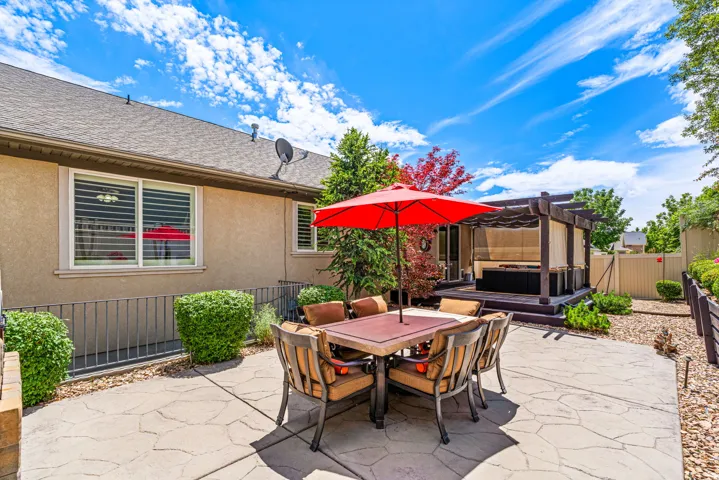 Stamped concrete patio featuring an outdoor dining area, a built-in pergola structure with a privacy screen, and mature landscaping