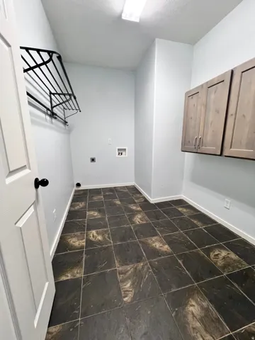Utility room featuring dark-toned square floor tiles and light-colored walls
