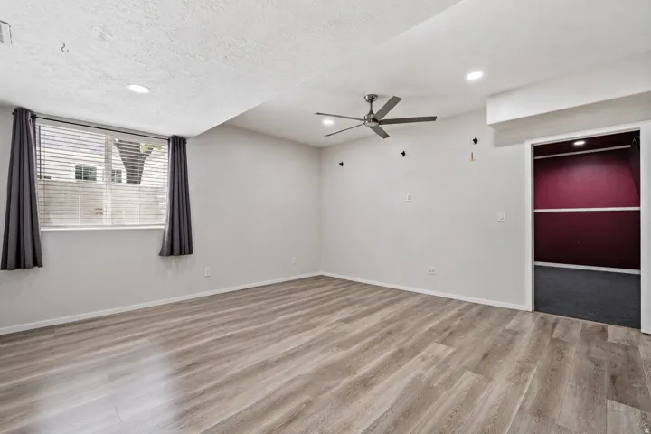 Spacious room featuring wood-finish flooring, recessed lighting, and a ceiling fan