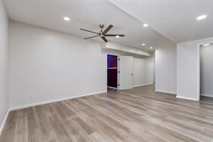 Spacious room featuring wood-finish flooring, recessed lighting, and a ceiling fan