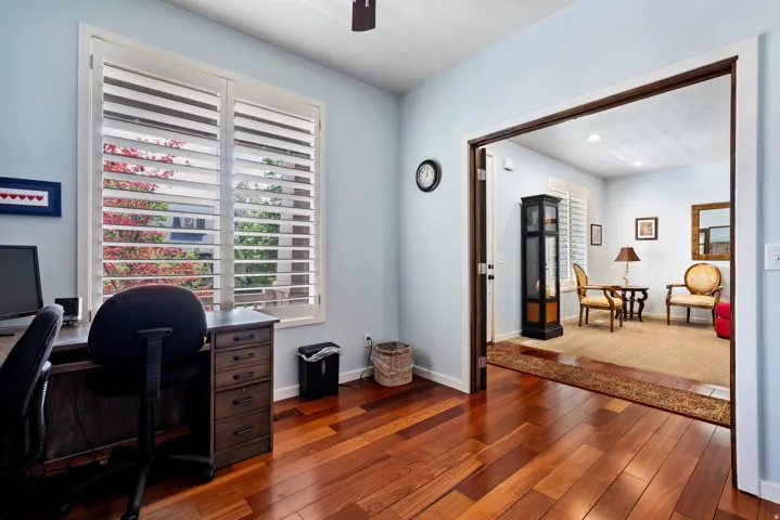 Warm wood-finish flooring extending into an entryway with a wide doorway