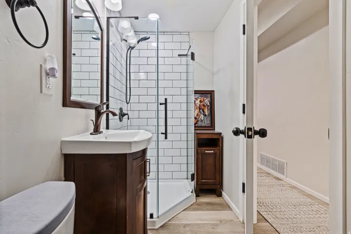 Bathroom featuring a dark wood-finish vanity with an integrated white sink, bronze-finish faucet, and coordinating framed mirror