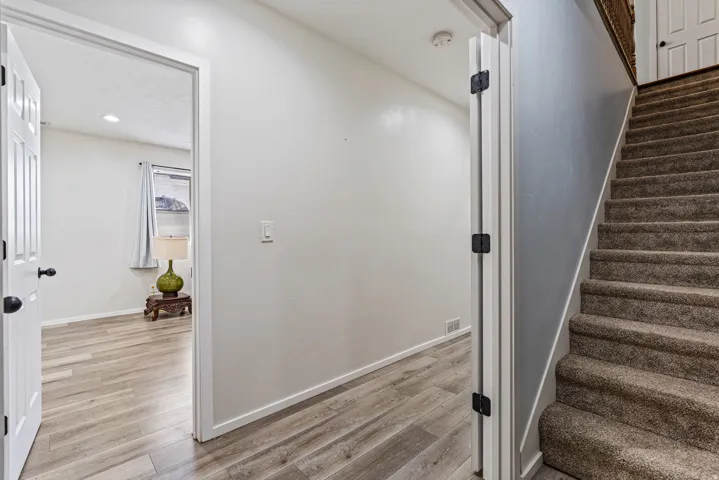 Interior doorway opening to a room featuring light wood-finish flooring and a window with curtain