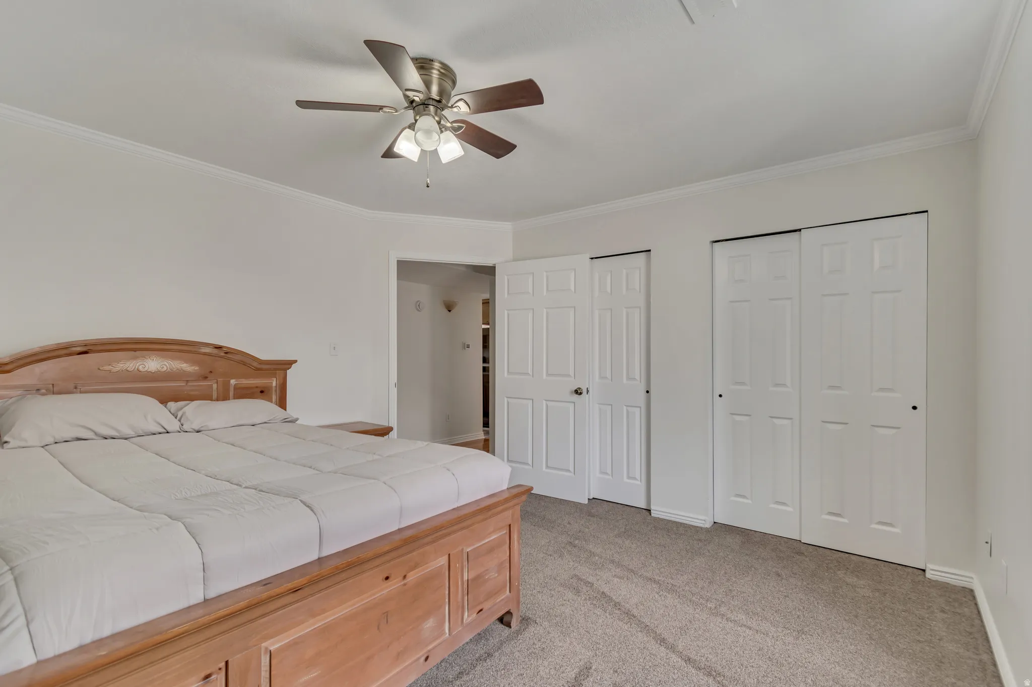 Bedroom featuring light-toned walls, crown molding, and carpet flooring