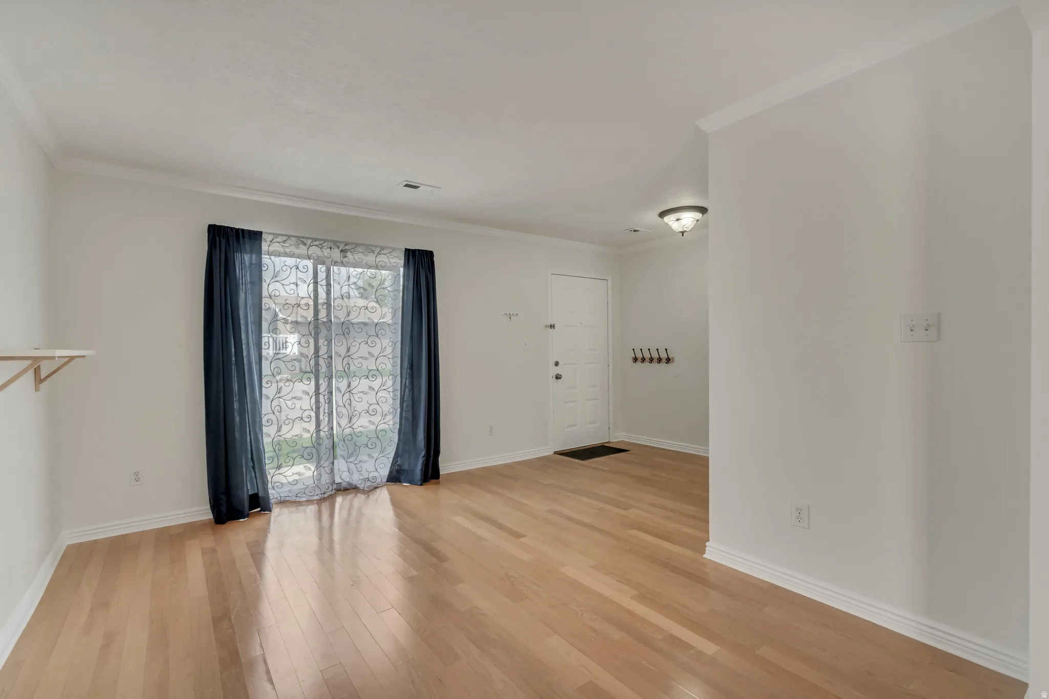 Open concept room featuring wood-finish flooring, white baseboards, and crown molding