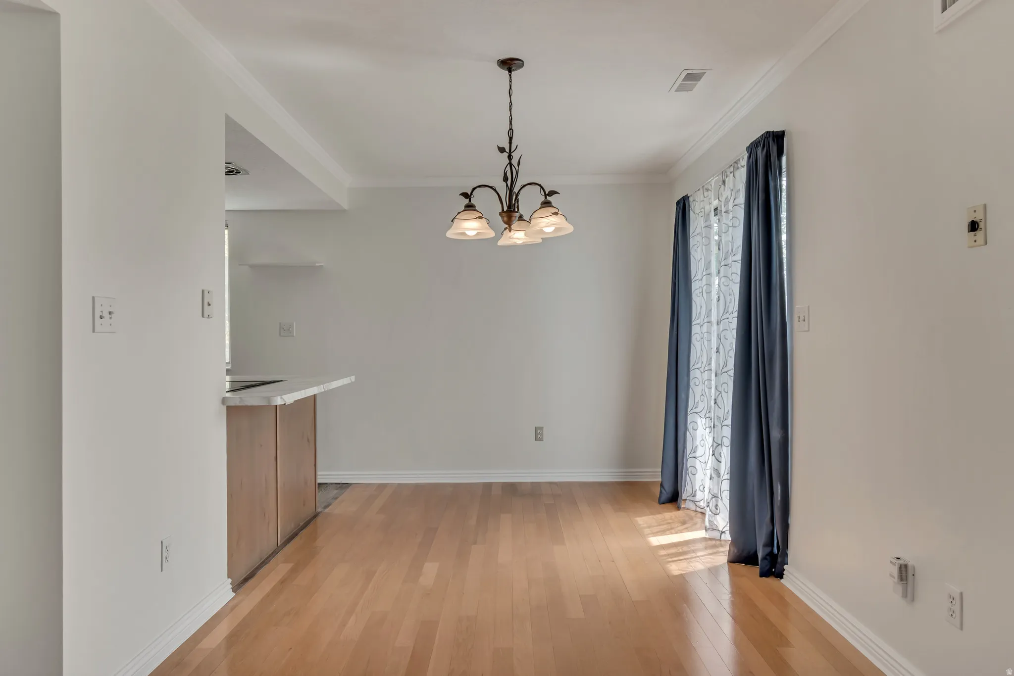 Hardwood-style flooring throughout, crown molding, and a bronze chandelier
