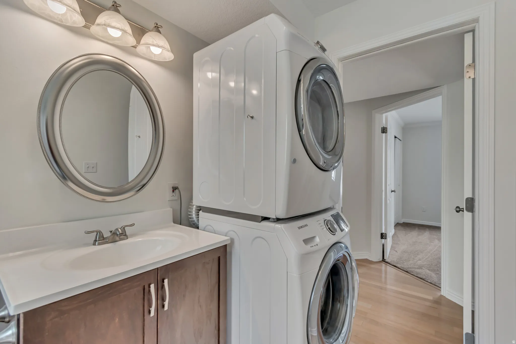 Bathroom featuring a single vanity with wood-finish cabinetry, a white countertop, and a circular mirror