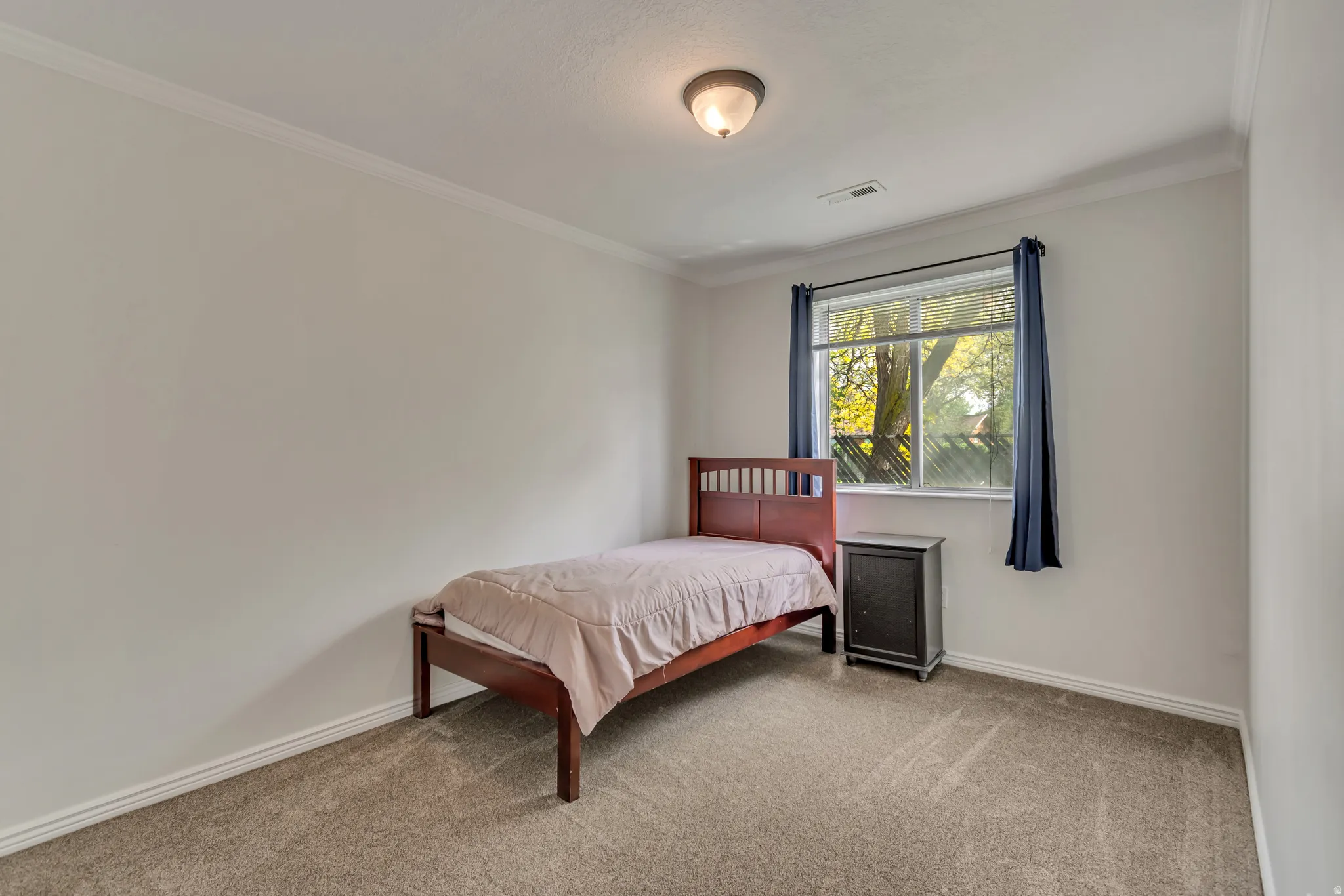 Carpeted room featuring a large window, crown molding, baseboards, and a flush mount ceiling light