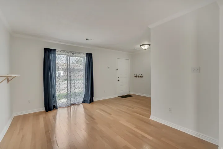 Open concept room featuring wood-finish flooring, white baseboards, and crown molding