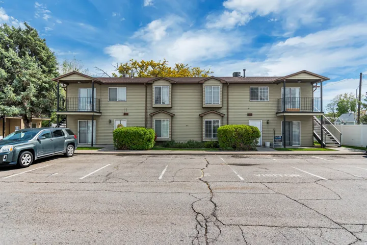 Multi-unit building featuring tan siding and multiple balconies with dark metal railings