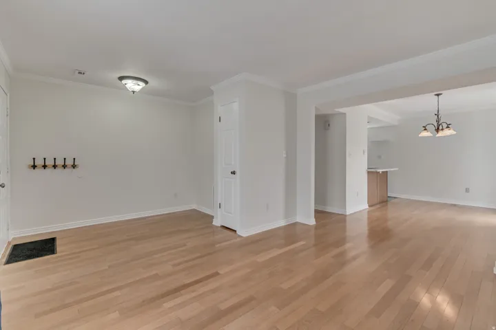 Spacious room featuring light wood-finish flooring, white walls, and crown molding