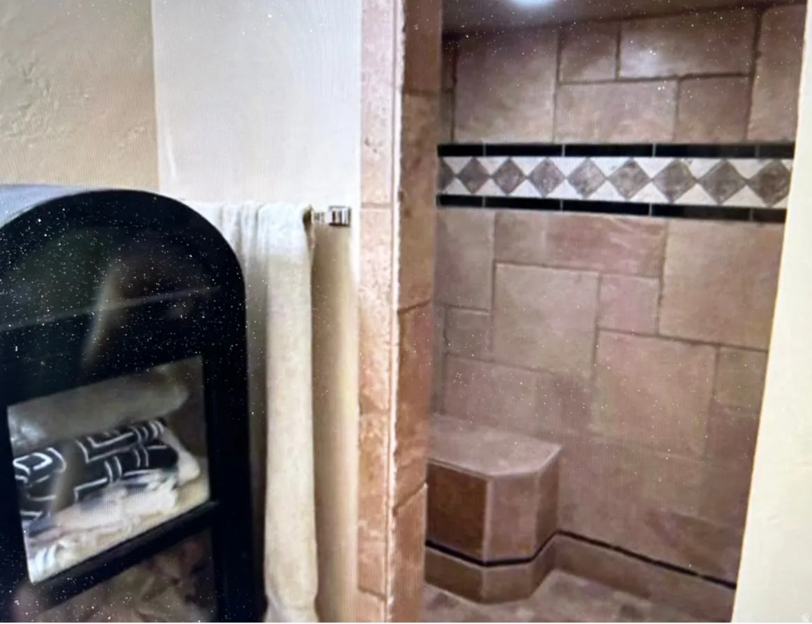 Spacious walk-in shower featuring large format stone-look tile, decorative accent band, and a built-in bench