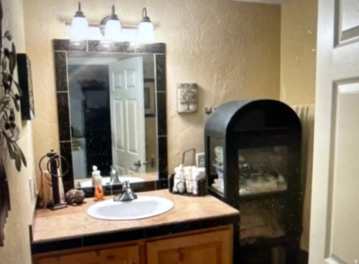 Bathroom vanity featuring an oval undermount sink, a tiled countertop, and a tiled mirror surround