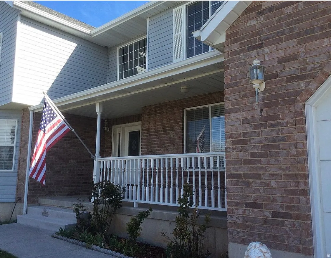 Brick and siding exterior featuring a covered porch, white railing, and decorative outdoor lighting
