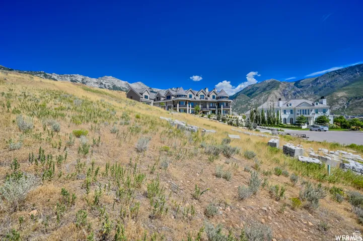 Expansive hillside property featuring two distinct architectural styles, a paved road, and a dramatic mountain backdrop