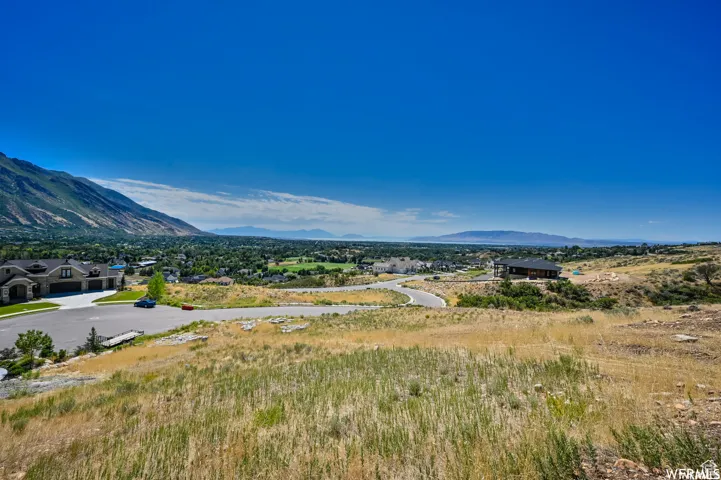 Expansive hillside landscape with distant mountain ranges and a visible body of water