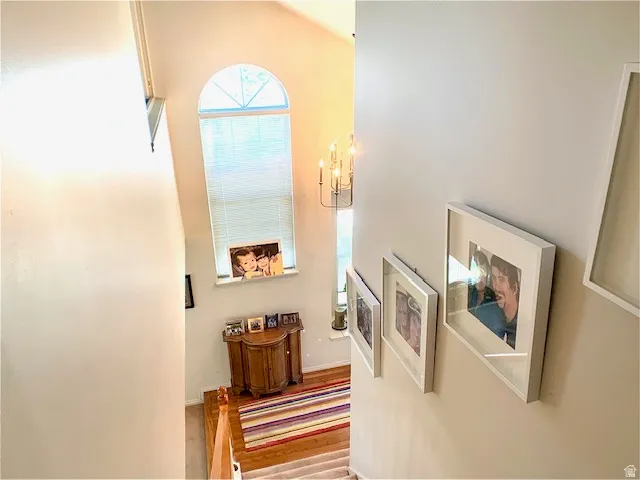 Grand foyer featuring a vaulted ceiling with an arched transom window, a multi-tier chandelier, wood-finish flooring, and a light neutral color palette