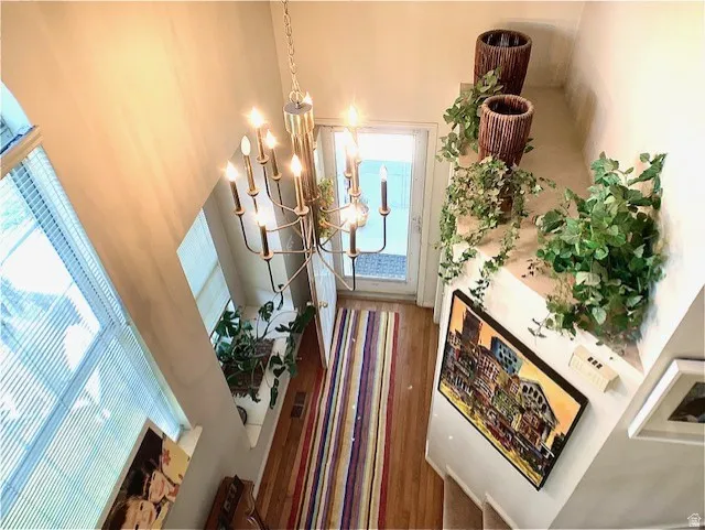 Two-story entry featuring a multi-light chandelier, hardwood flooring, and abundant natural light from upper and lower windows