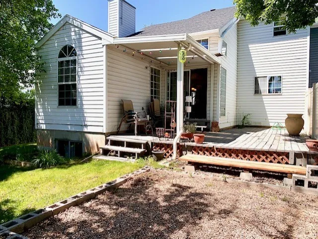 Rear exterior featuring a covered patio, wood deck, and white siding