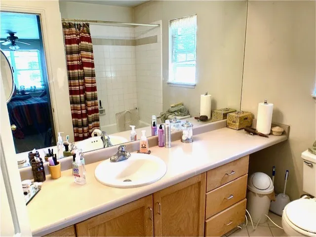 Primary Bathroom featuring a light-toned vanity with an integrated sink, a large mirror, and a window with blinds