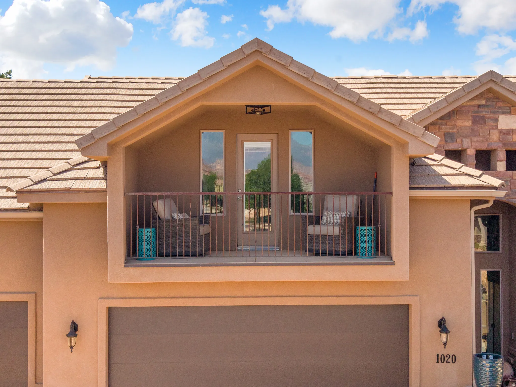 Stucco exterior featuring a tiled roof and an upper-level balcony with metal railings