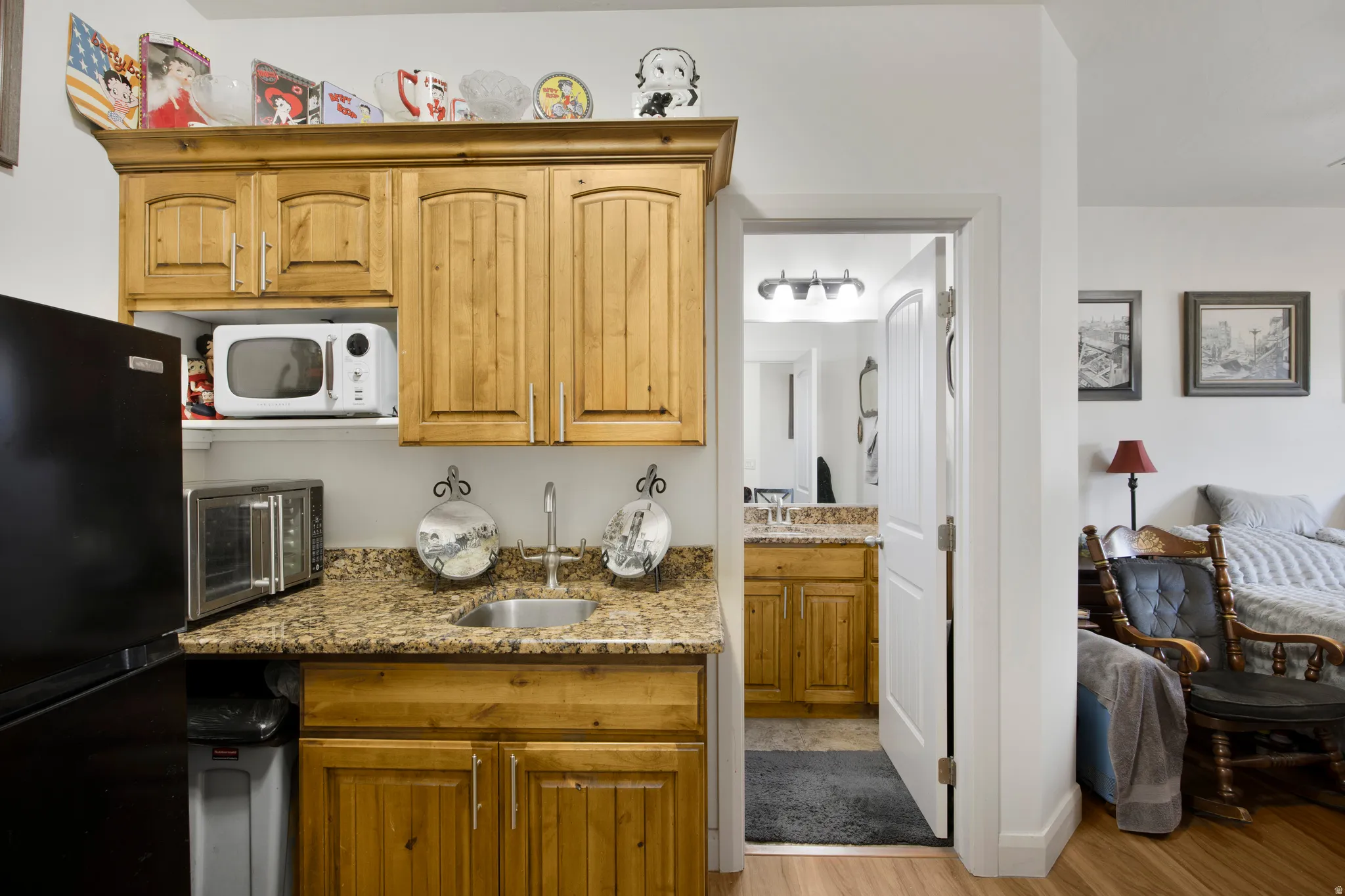 Kitchenette featuring wood cabinetry, granite-finish countertops, and a stainless steel sink