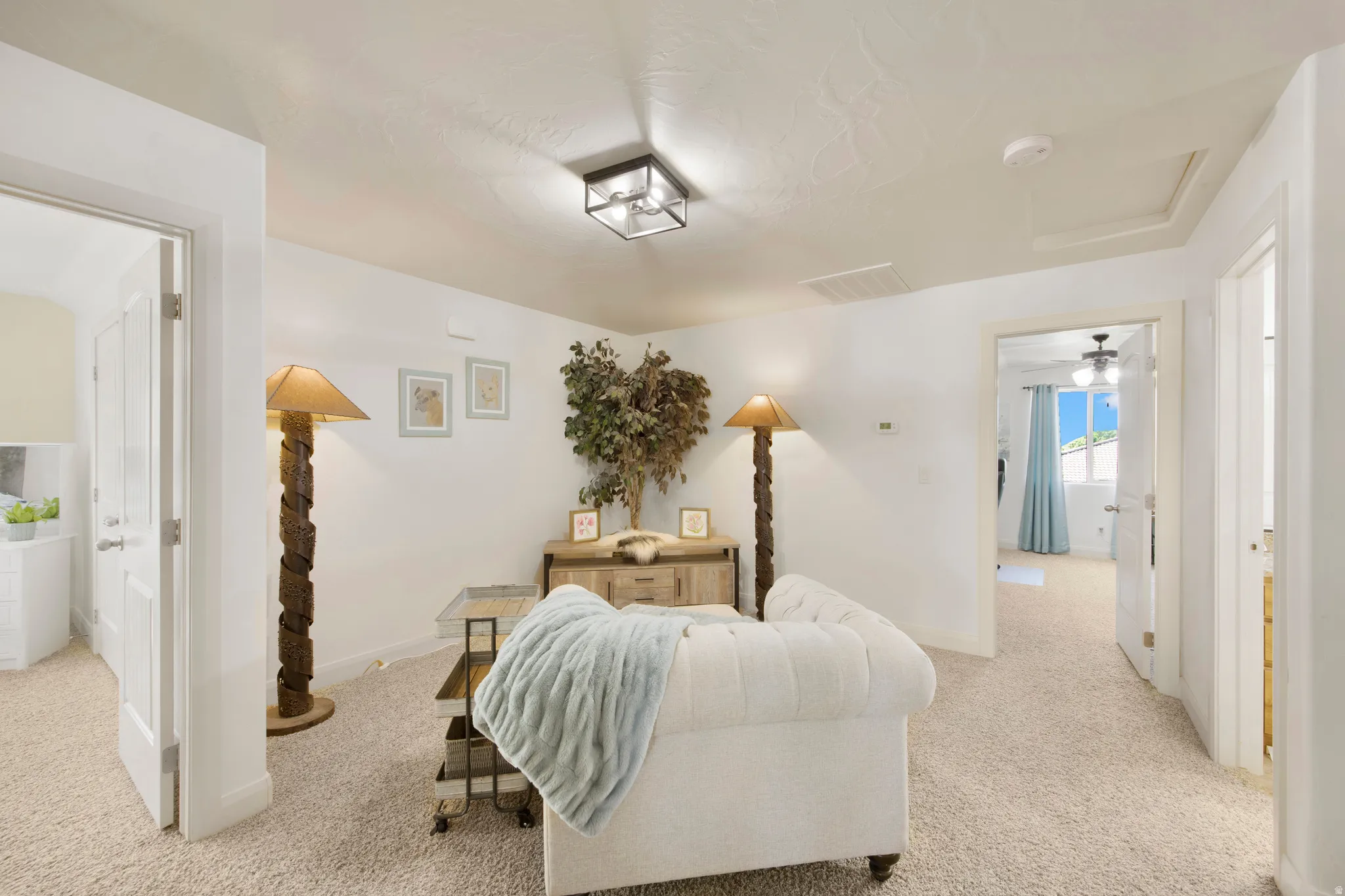 Carpeted common area featuring white walls, a flush-mount ceiling light fixture, and multiple doorways