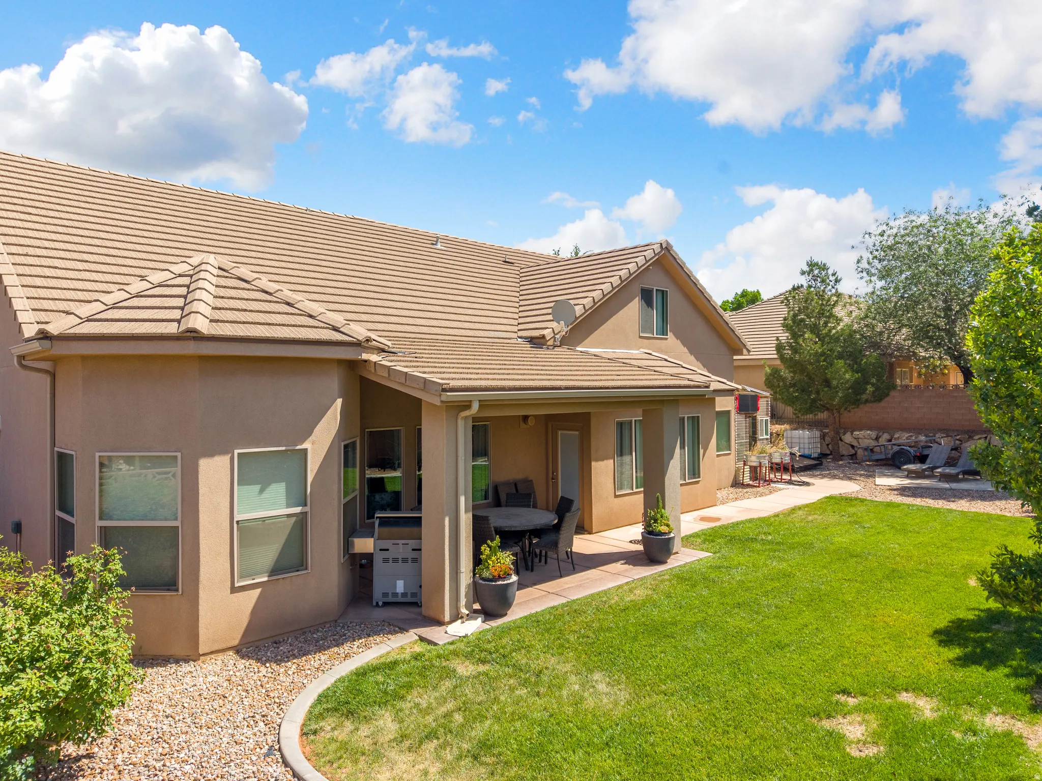 Expansive backyard with a covered patio, manicured lawn, and decorative rock landscaping