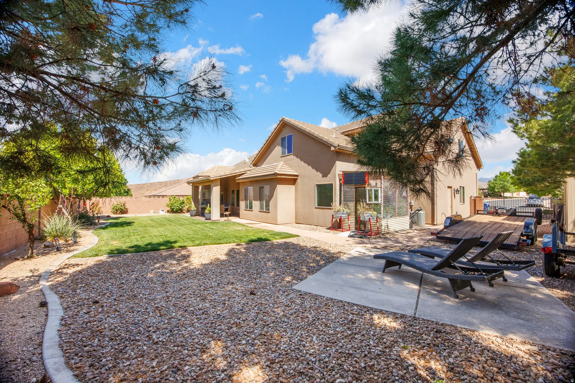 Expansive backyard featuring a large stucco exterior, a patio area, and a xeriscaped section with decorative gravel