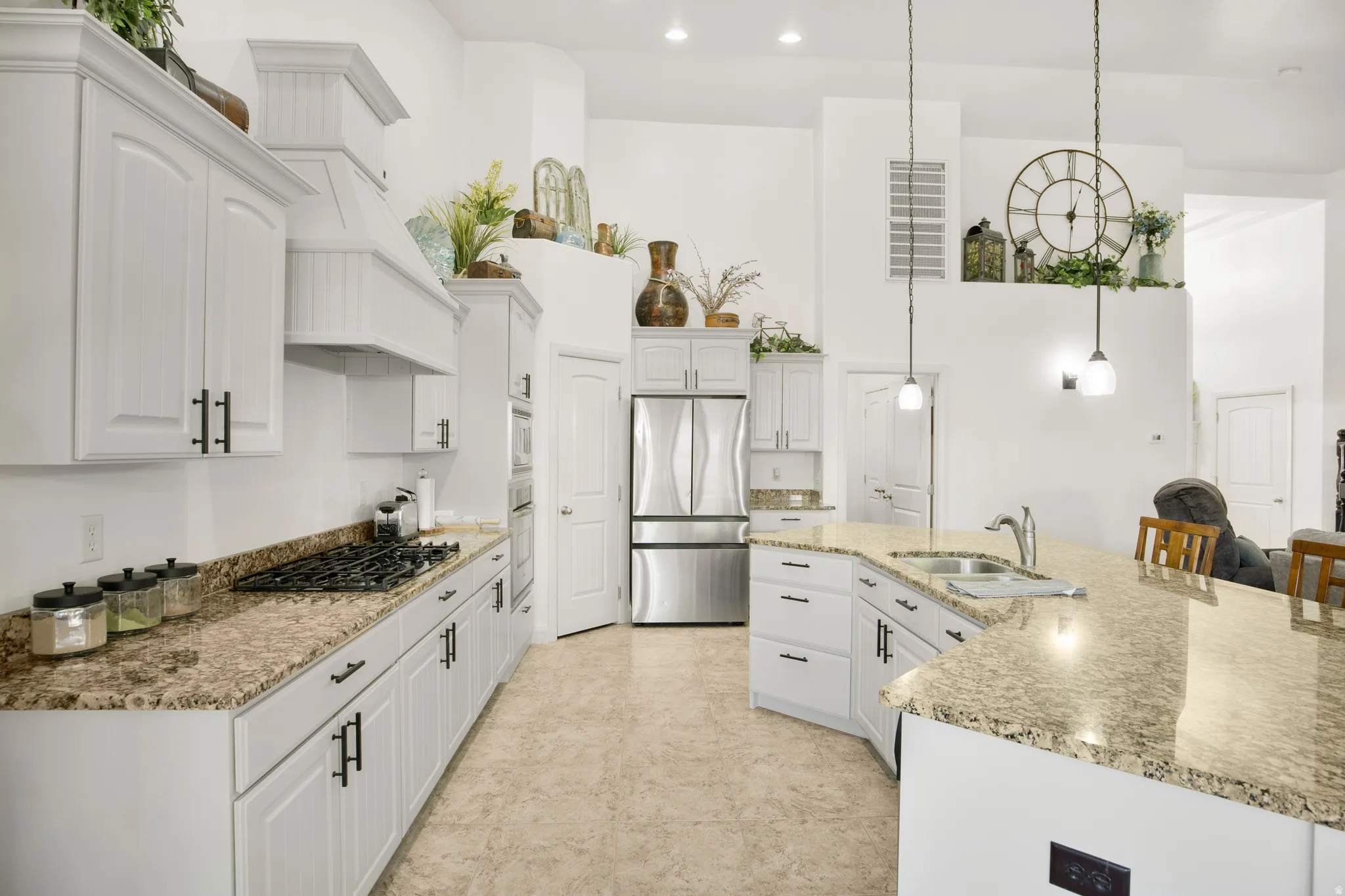Kitchen featuring white cabinetry with dark hardware, a gas range with a matching range hood, stainless steel appliances, and light-toned granite countertops