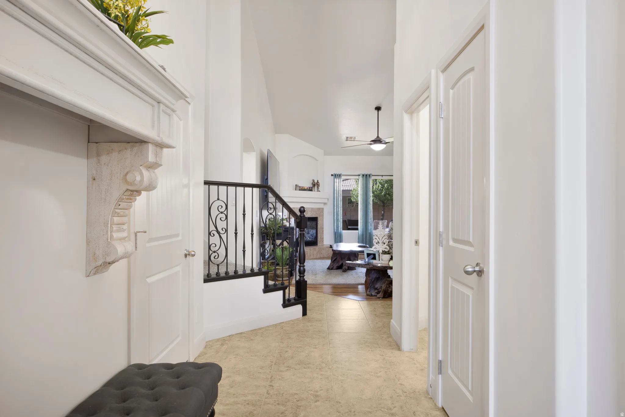 Entryway featuring tile flooring, a decorative wall shelf, and a staircase with wrought iron balusters