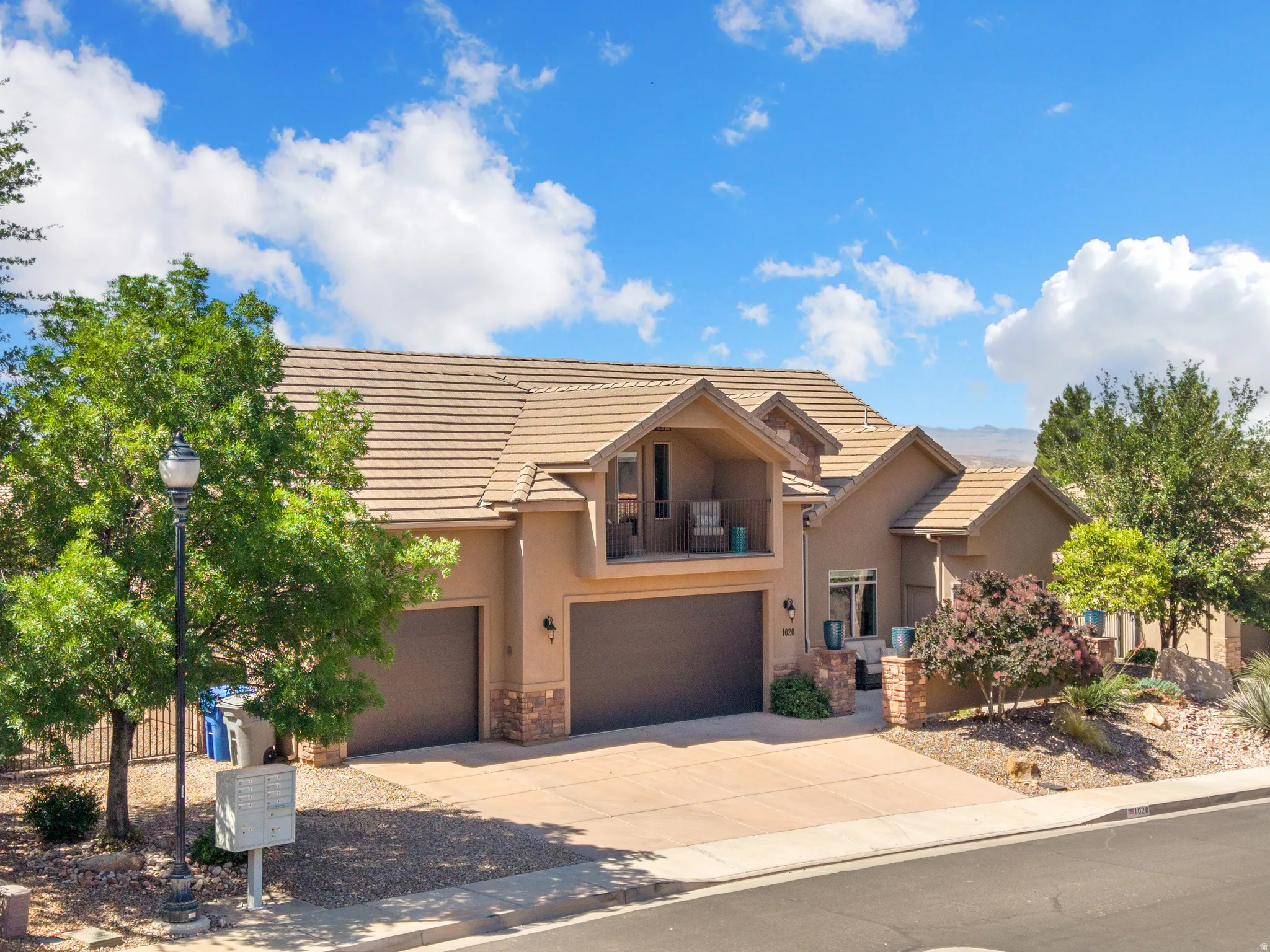 Stucco exterior with a tile roof, featuring a two-car garage, a single-car garage, and an upper-level balcony