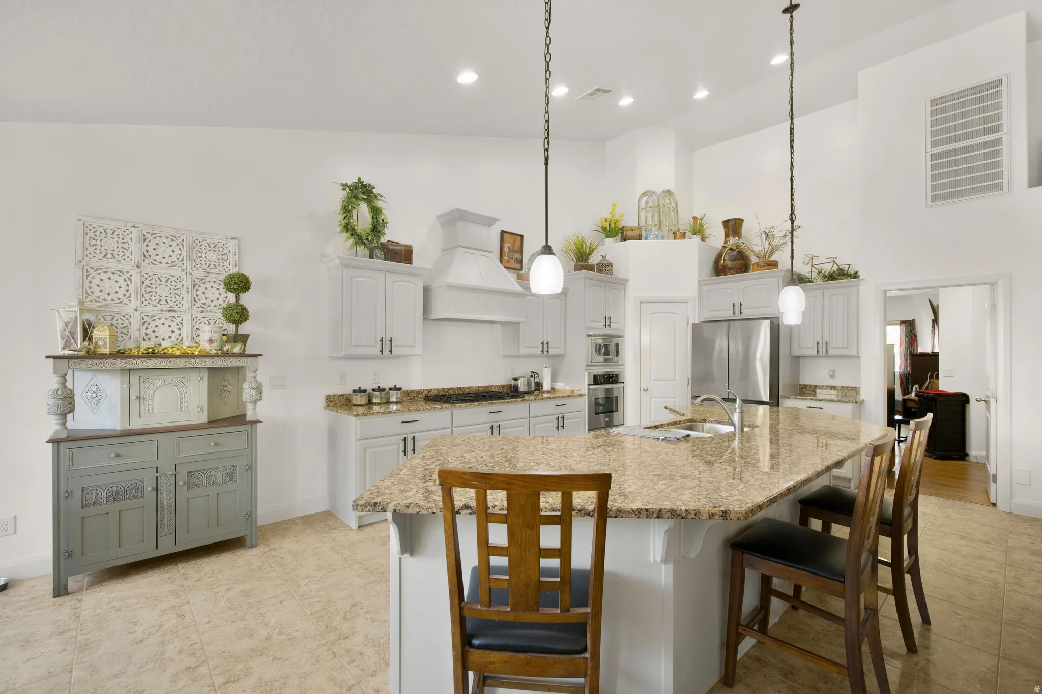 Kitchen featuring a large island with a stone countertop, light-toned cabinetry, stainless steel appliances, and tile flooring
