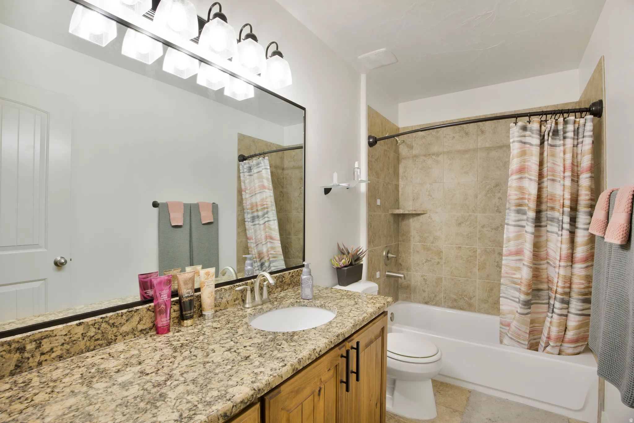 Bathroom vanity with stone countertop and integrated sink, complemented by a large framed mirror and a six-light fixture