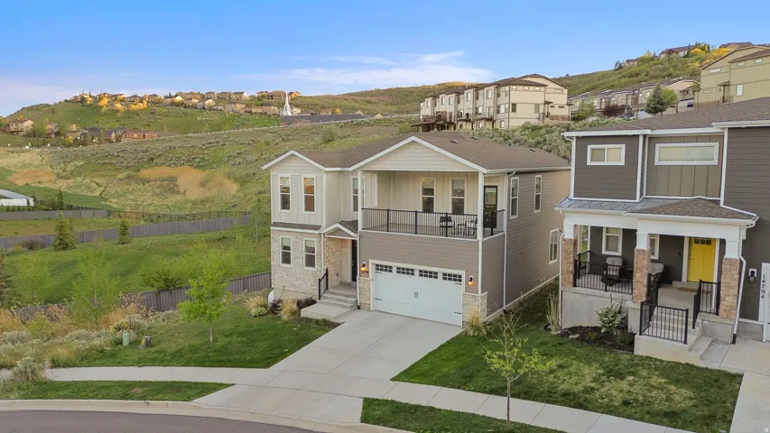 Two-story residence featuring a ground-level garage and upper-level balcony with black iron railings