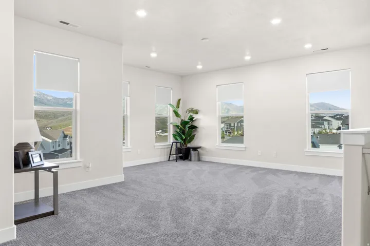 Spacious carpeted room featuring multiple windows with mountain and neighborhood scenery