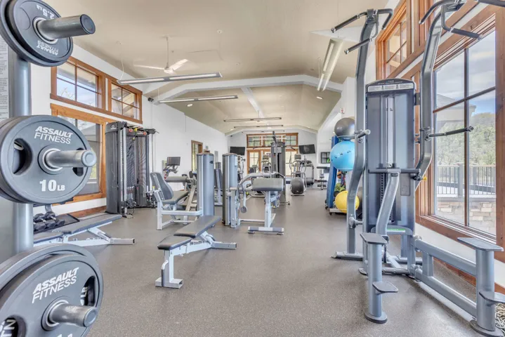 Dedicated fitness area featuring multiple exercise machines, weight racks, and rubber flooring
