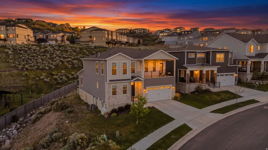 Contemporary multi-level home featuring a stone and siding exterior, two-car garage, and an upper-level balcony