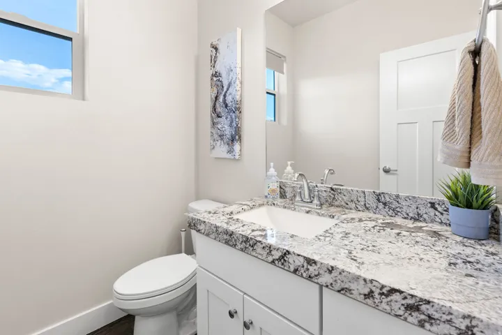 Bathroom featuring a white vanity with an undermount sink, speckled countertop, and chrome faucet