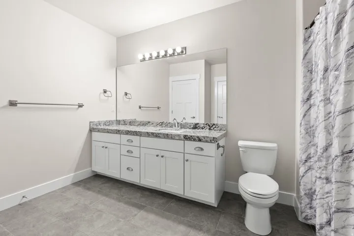 Double vanity with a speckled countertop, white cabinetry, and brushed nickel hardware