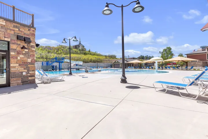 Expansive aquatic area featuring multiple swimming pools, water slides, a built-in water feature, and a surrounding concrete deck with shaded lounging areas