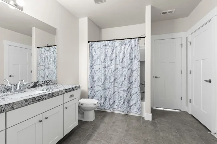 Bathroom featuring a double vanity with stone countertop, undermount sinks, and chrome fixtures