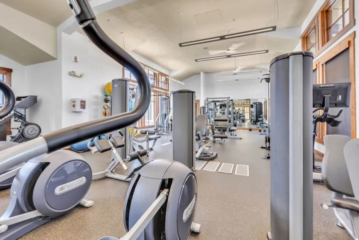 Fitness center with vaulted ceilings, recessed linear lighting, and multiple windows